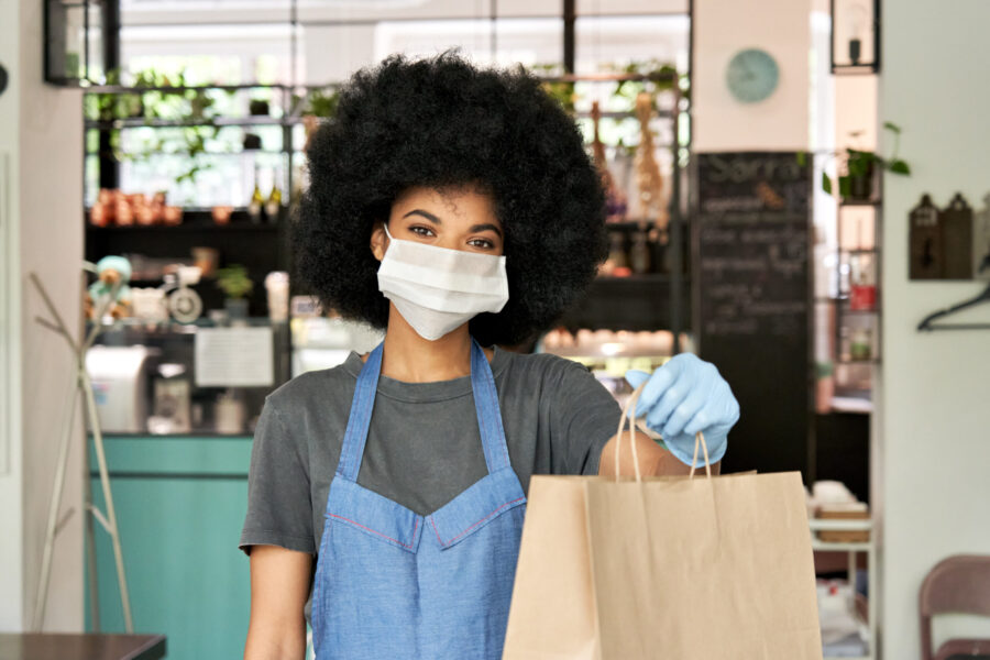 african american waitress offering takeout to customer after successfully using a takeout pos system