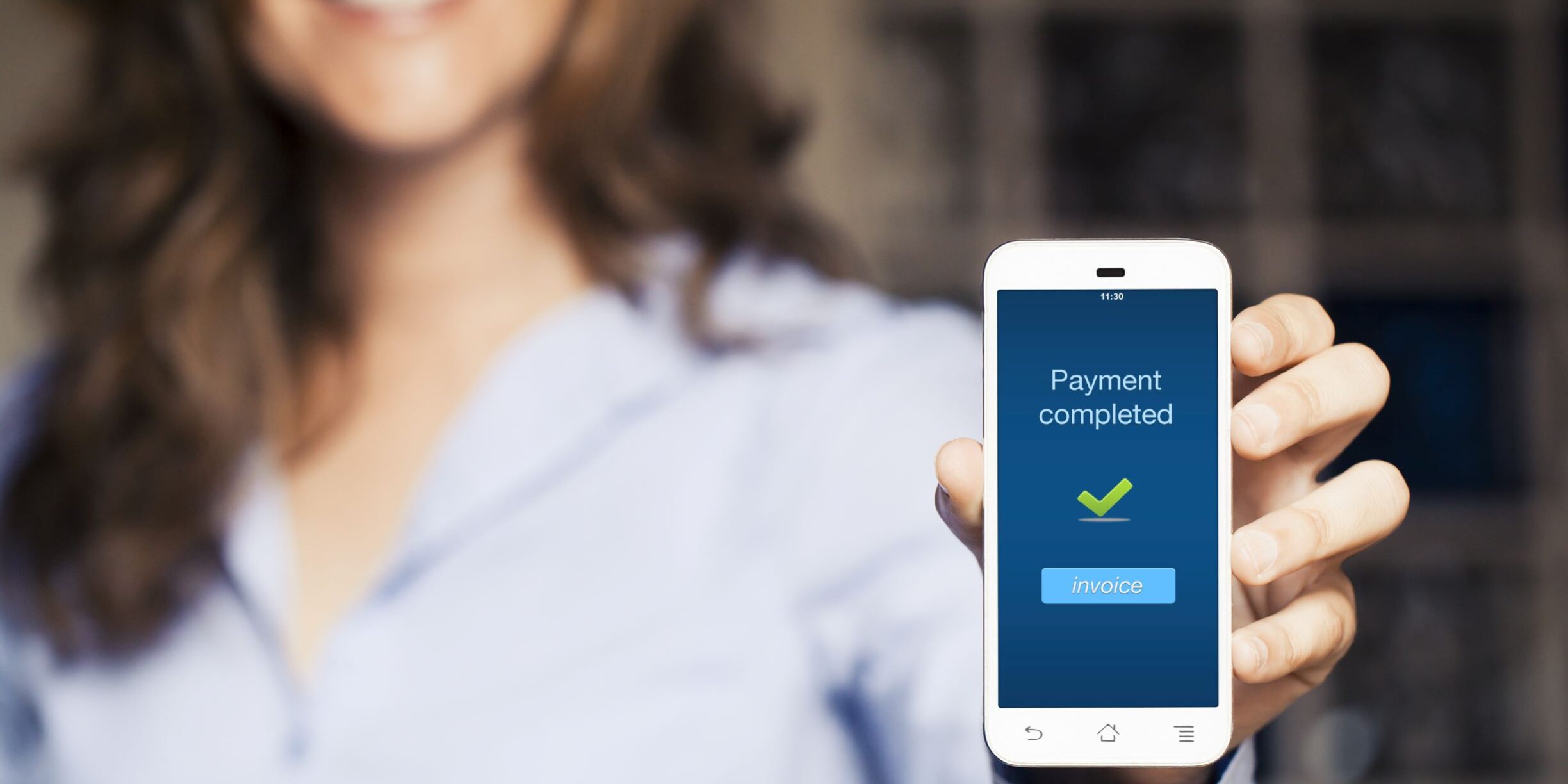 woman holds mobile device up to show touchless payment has been made