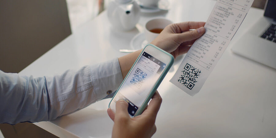 Close up of woman using smartphone and scanning qr code on cash shop receipt. Female client in restaurant scanning qr-code on bill to get discount or to tip