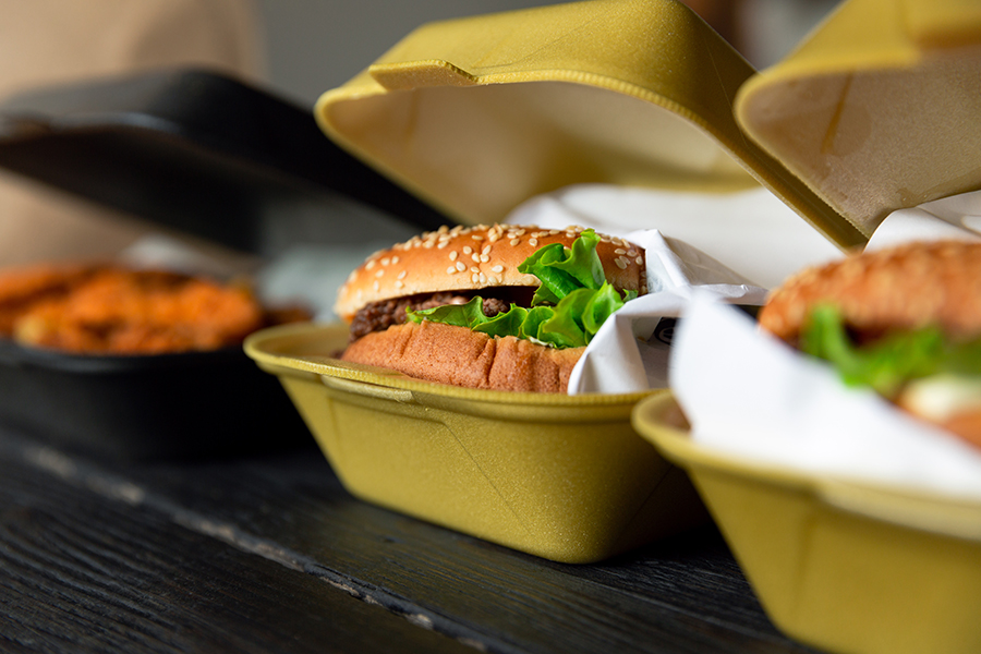 Hamburger in a takeaway container on the wooden background. Food