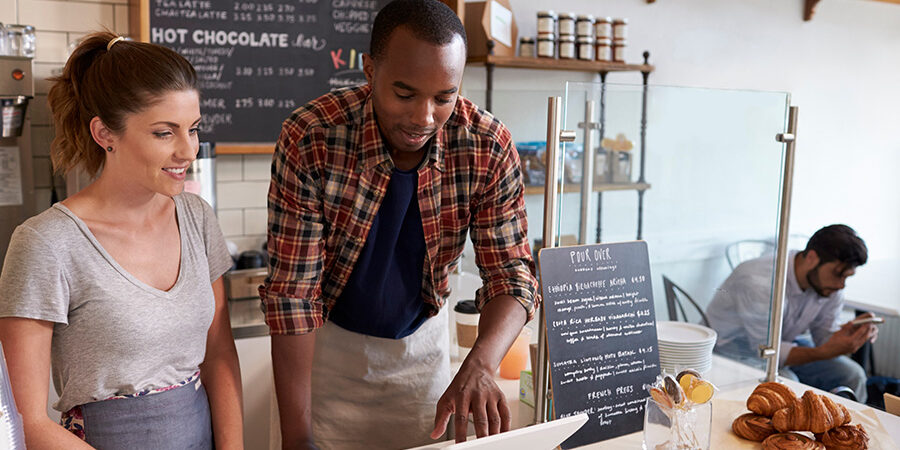 Barista at coffee shop showing till to new employee, close up Barista at coffee shop performing POS training