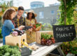 Female gardener selling organic crops and picking up a bountiful basket full of fresh produce