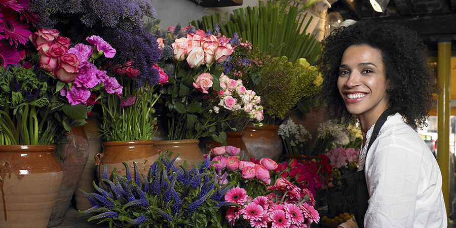 Young female florist holding flowers Florist with a radiant smile surrounded by colorful blooms in a cozy flower shop.